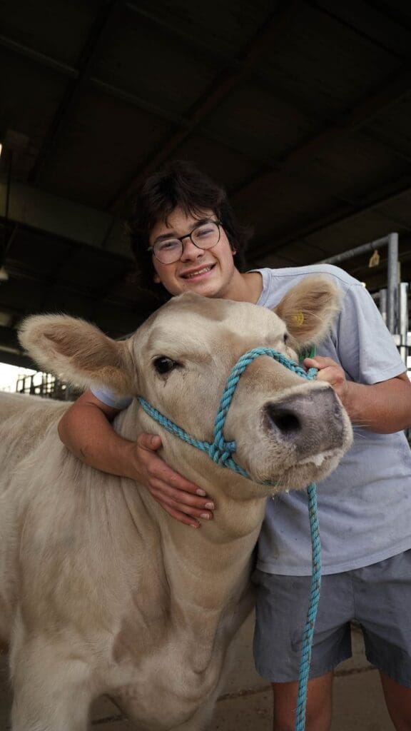 Student posing with a cow.