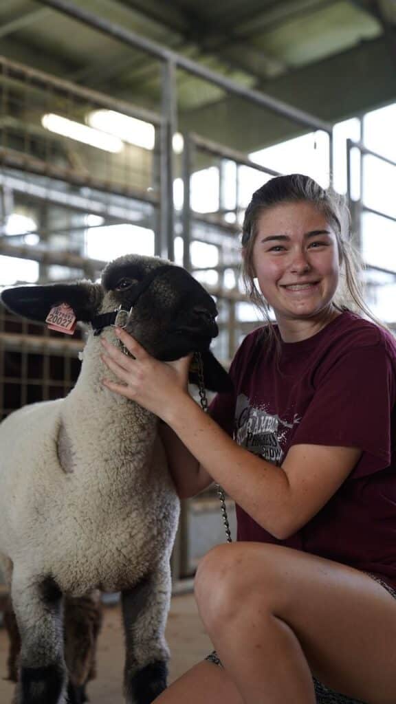 Student posing with a sheep.