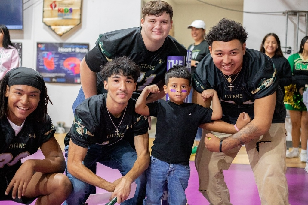 SW Legacy football players posing with elementary student