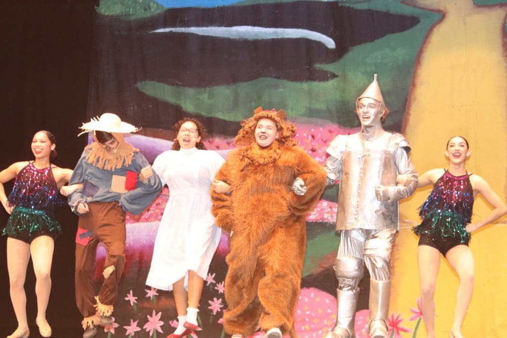 Scarecrow, Dorothy, Cowardly Lion, Tin Man, and company dancing