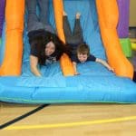 students and teachers sliding down bounce house