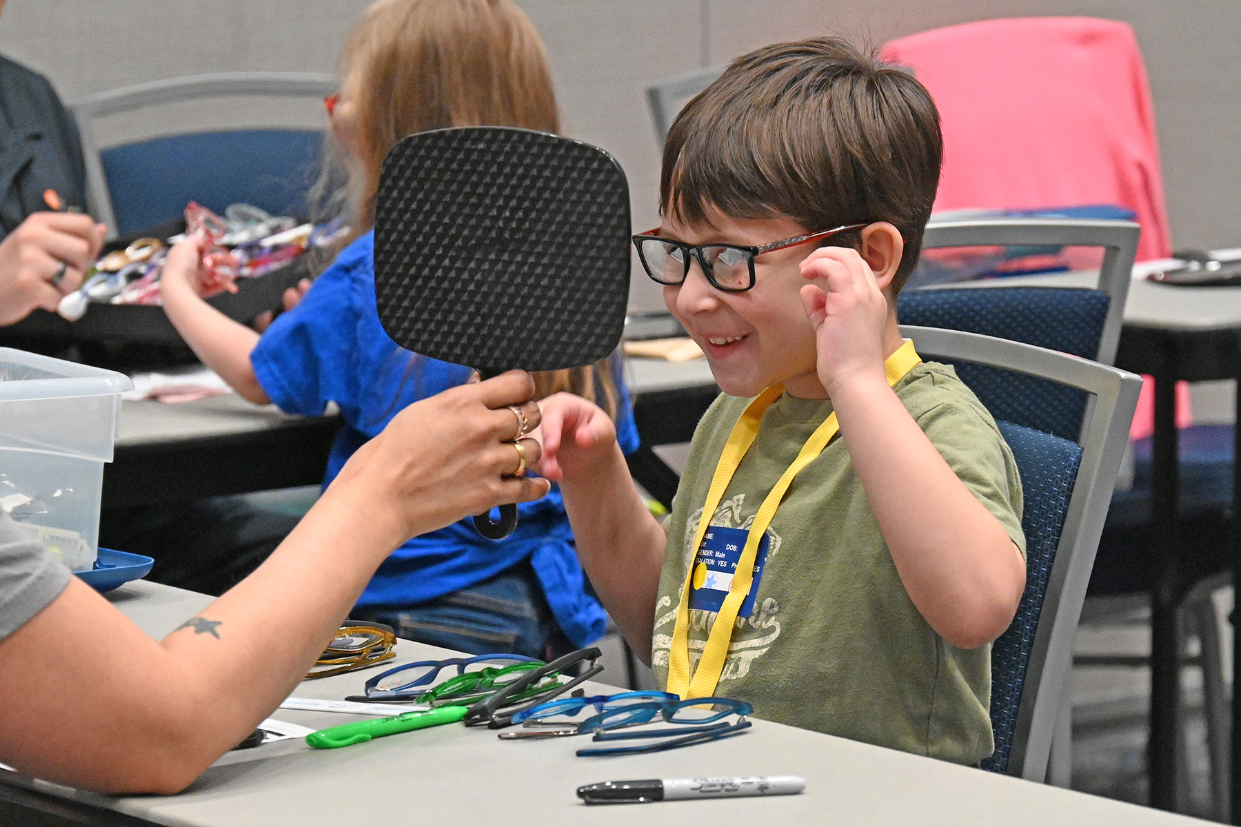 Cypress-Fairbanks Vision Care Kid smiling and looking at glasses in mirror