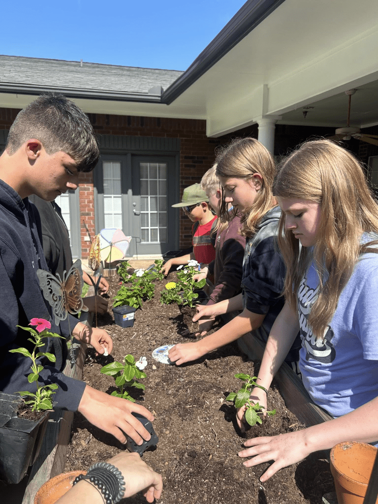 Woodville ISD students planting flowers at The Orchard Assited Living center