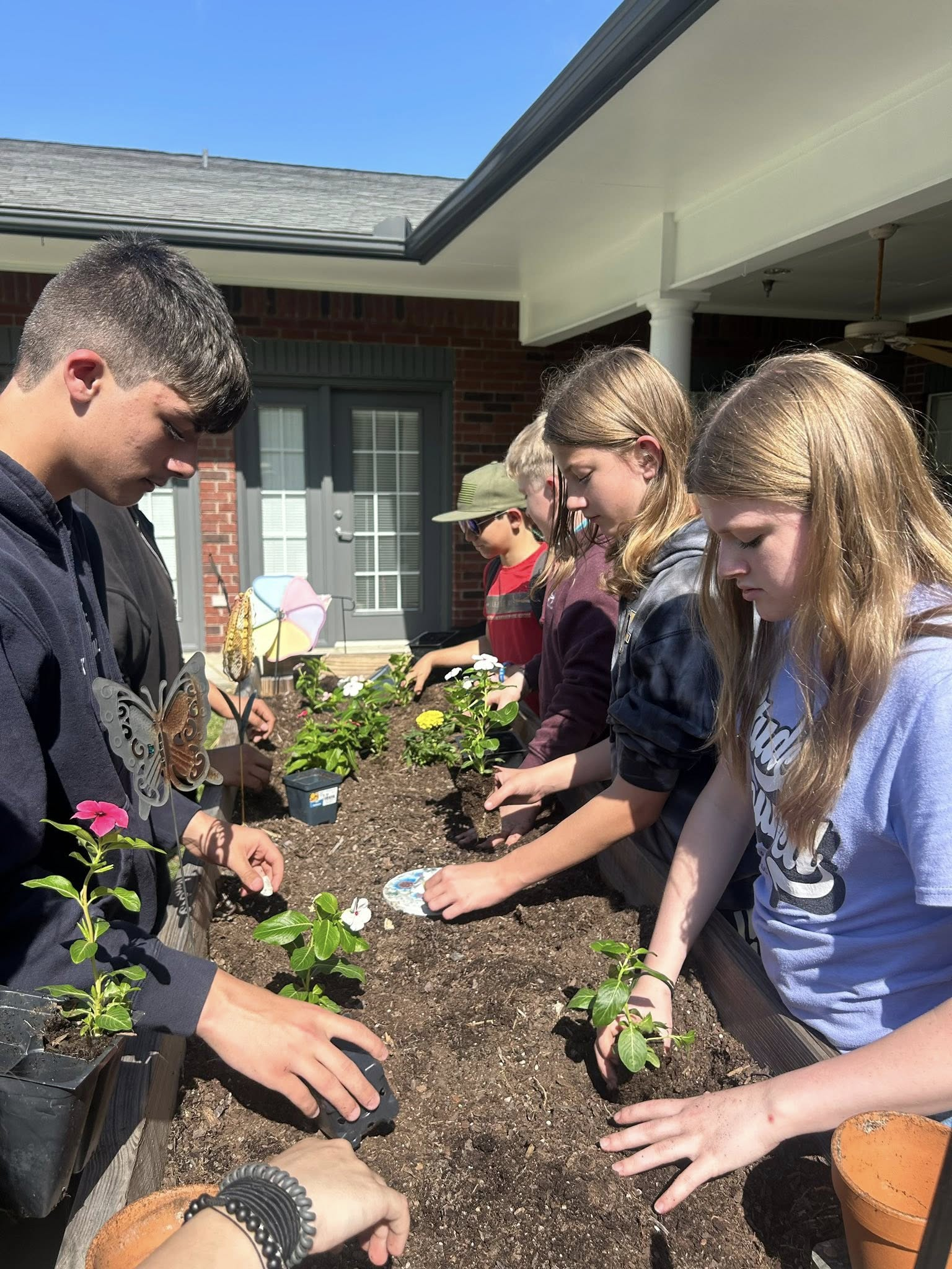 Woodville ISD students planting flowers at The Orchard Assited Living center