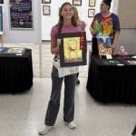 Forney ISD Student holds up an art piece at the Hispanic Heritage Art Show