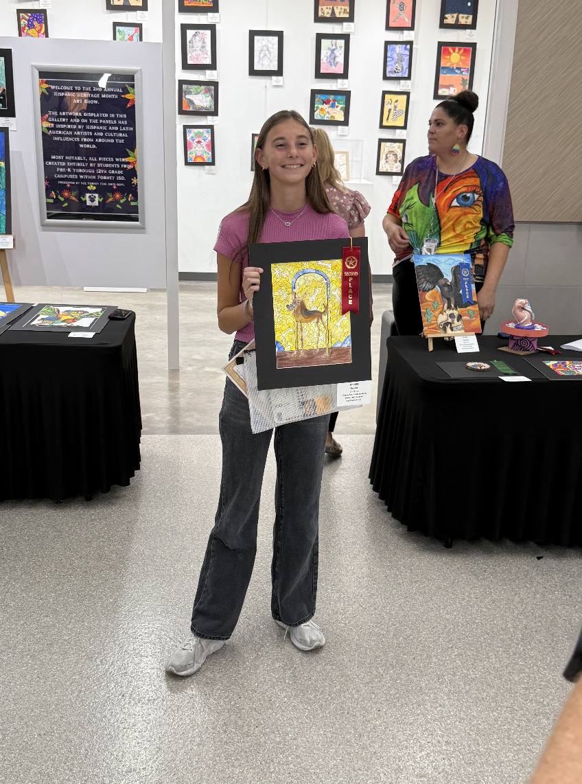 Forney ISD Student holds up an art piece at the Hispanic Heritage Art Show