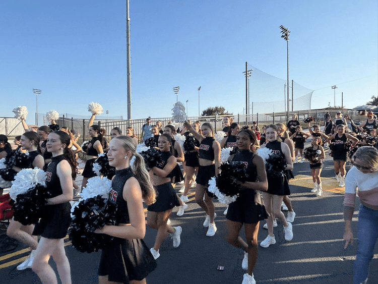 A large squad of student cheerleaders walking down the street.